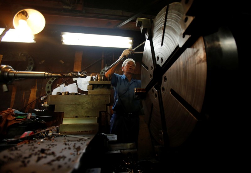 © Reuters. FILE PHOTO:  A man produces machine parts inside a factory in Tokyo