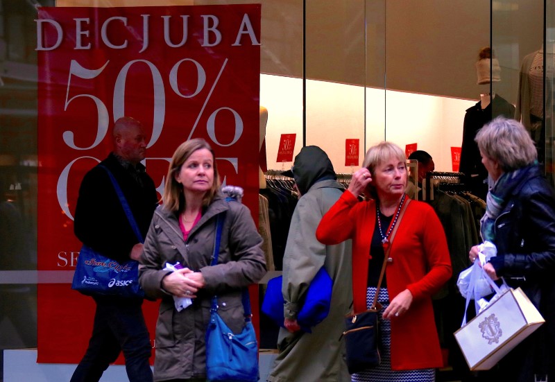 © Reuters. FILE PHOTO: Shoppers stand outside a retail store displaying a sales sign in central Wellington, New Zealand