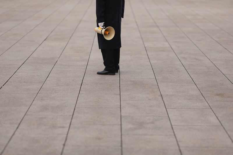 © Reuters. A security agent holds a megaphone at Tiananmen Square a day before the 19th National Congress of the Communist Party of China begins in Beijing