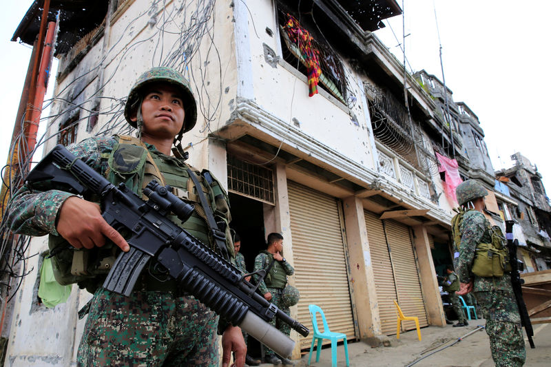 © Reuters. Government soldiers stand guard in front of damaged building and houses in Sultan Omar Dianalan boulevard at Mapandi district in Marawi city