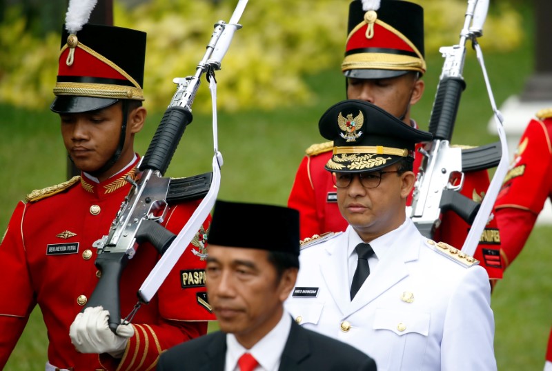 © Reuters. Presidential guards walk with Indonesia President Joko Widodo and Jakarta Governor Anies Baswedan for a swearing-in ceremony at the Presidential Palace in Jakarta