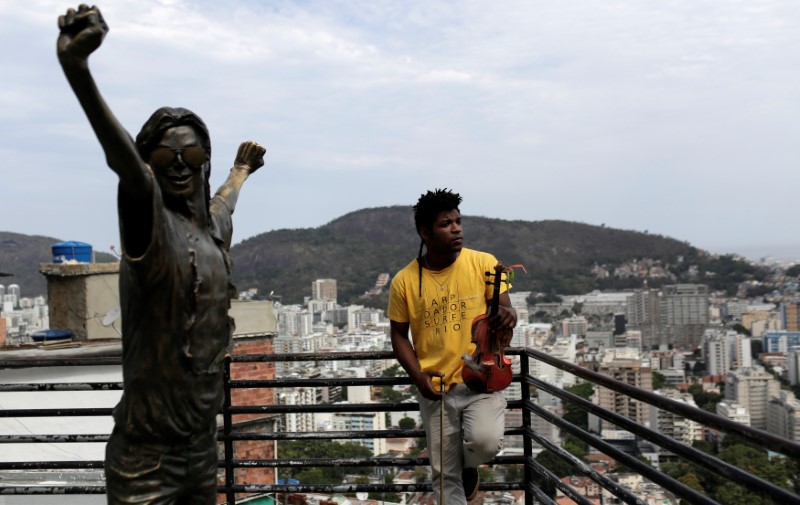 © Reuters. Paulo Maurício Dias posa para foto segurando seu violino ao lado da estátua de Michael Jackson na favela Santa Marta, no Rio de Janeiro