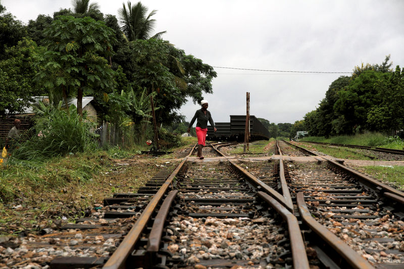 © Reuters. FILE PHOTO: A woman crosses a railway line at Dondo, near Beira port