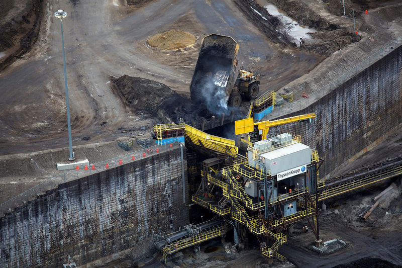 © Reuters. FILE PHOTO - Giant dump trucks dump raw tar sands for processing at the Suncor tar sands mining operations near Fort McMurray