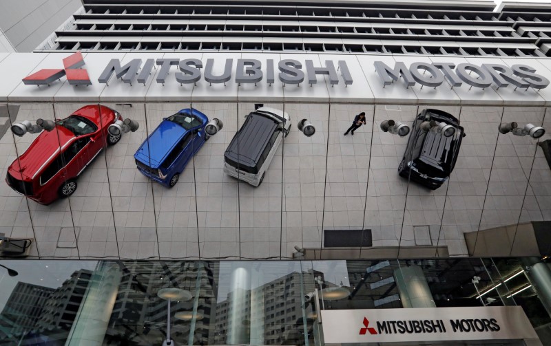 © Reuters. Mitsubishi Motors Corp's vehicles and a woman are reflected on an external wall at the company headquarters in Tokyo