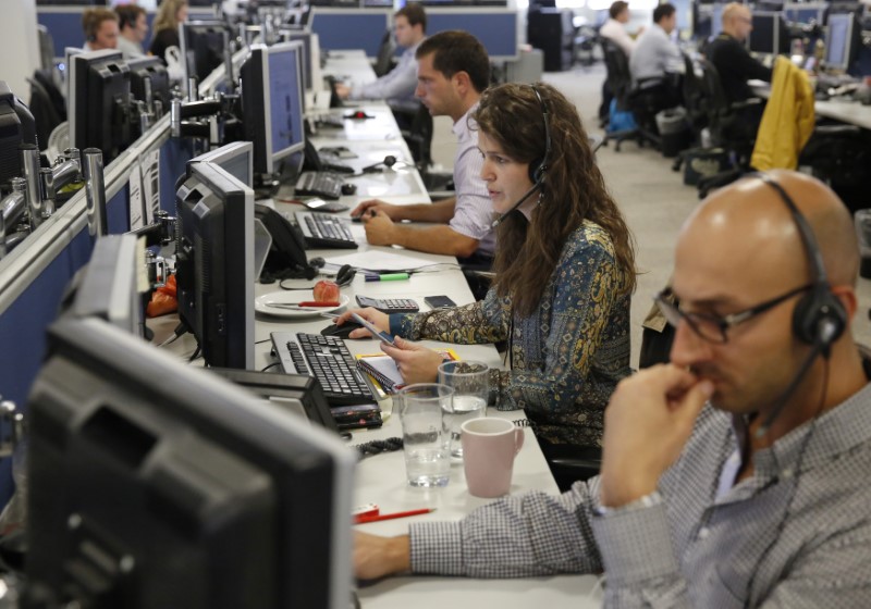 © Reuters. Traders sit at their desks at IG Index in London
