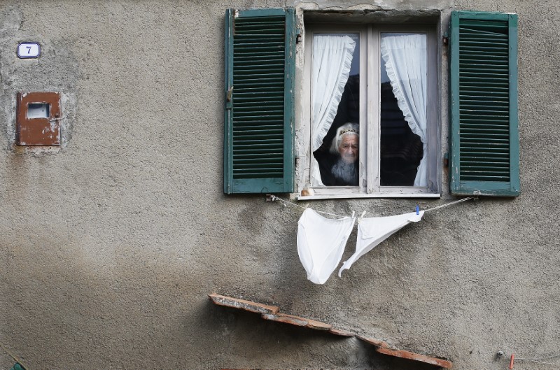 © Reuters. A woman looks out from a window of a building on Giglio Island
