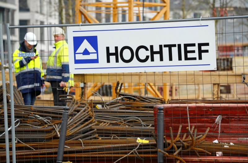 © Reuters. Workers of German construction company Hochtief stand next to the company's logo in Essen
