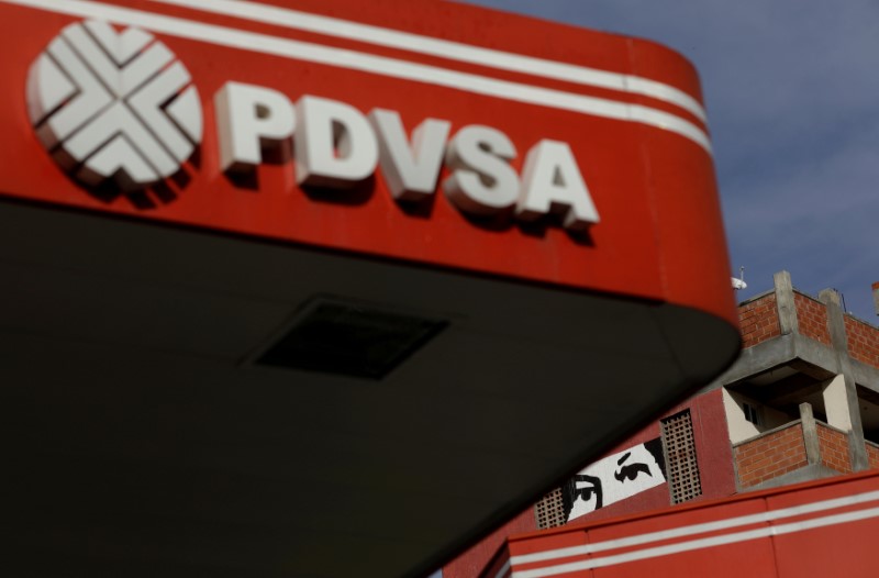 © Reuters. FILE PHOTO: A painting depicting the eyes of Venezuela's late President Hugo Chavez, is pictured close to a corporate logo of the state oil company PDVSA at a gas station in Caracas