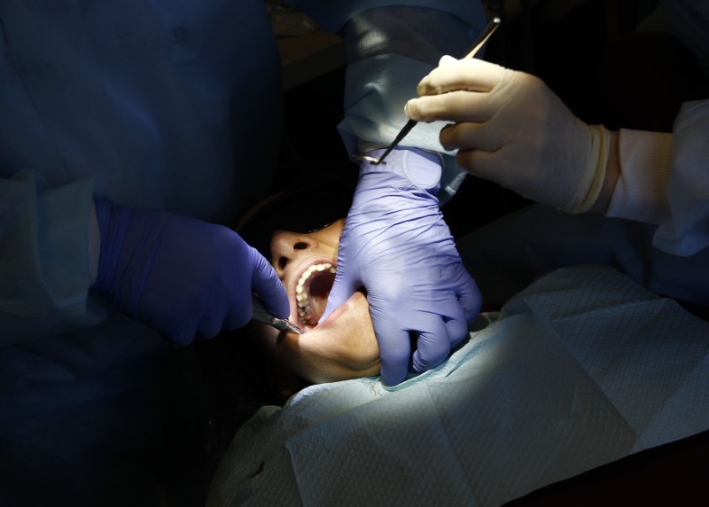 © Reuters. A dentist works on removing a tooth for a patient in Bloomingdale