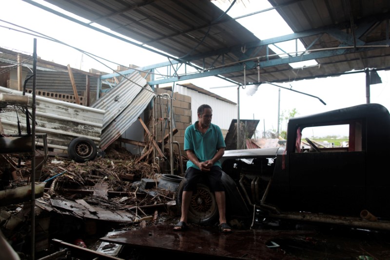 © Reuters. Freddy Guerrero sits amidst the remains of his auto shop, after the island was hit by Hurricane Maria in Toa Baja