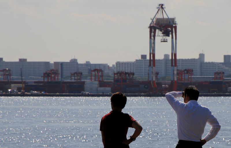 © Reuters. Men are seen in front of containers and cranes at an industrial port in Tokyo