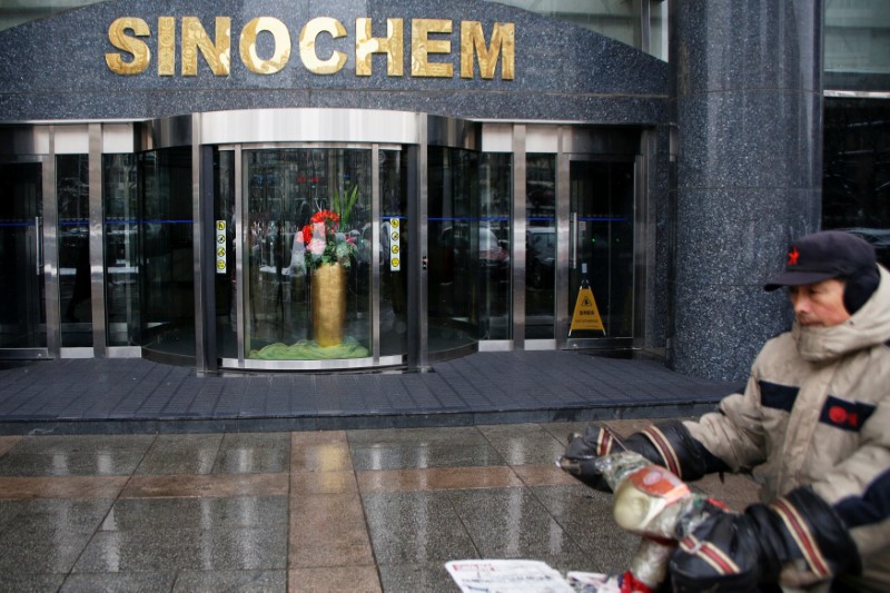 © Reuters. FILE PHOTO: A man rides past the office building of Sinochem in Beijing