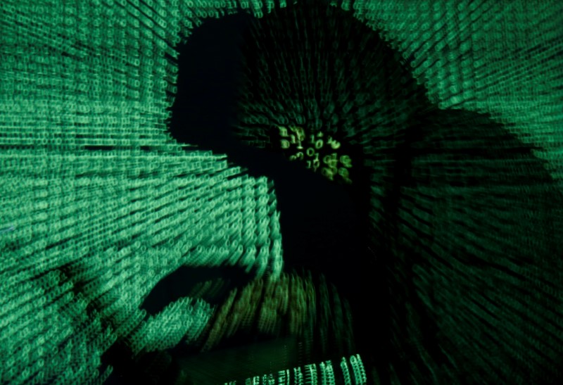 © Reuters. Man holds laptop computer as cyber code is projected on him in this illustration picture