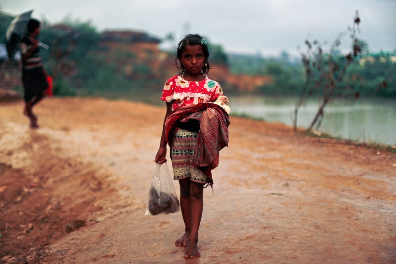 © Reuters. A Rohingya refugee girl poses with a chicken at Balukhali refugee camp near Cox's Bazar