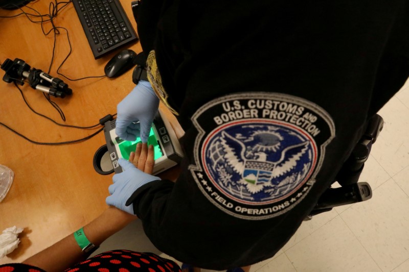 © Reuters. FILE PHOTO: A woman who is seeking asylum has her fingerprints taken by a U.S. Customs and Border patrol officer at a pedestrian port of entry from Mexico to the United States