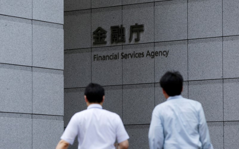© Reuters. FILE PHOTO: Men walk toward a sign of Japan's Financial Services Agency in Tokyo