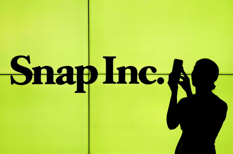 © Reuters. FILE PHOTO - A woman stands in front of the logo of Snap Inc. on the floor of the New York Stock Exchange in New York City