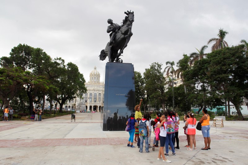 © Reuters. A school teacher explains about the bronze replica of a New York statue of Cuban independence hero Jose Marti after it's unveiling in the historic centre of Havana, Cuba