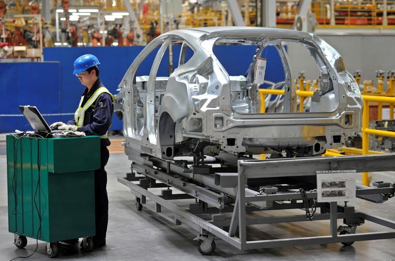 © Reuters. An employee uses a laptop next to a car body at an assembly line at a Ford manufacturing plant in Chongqing