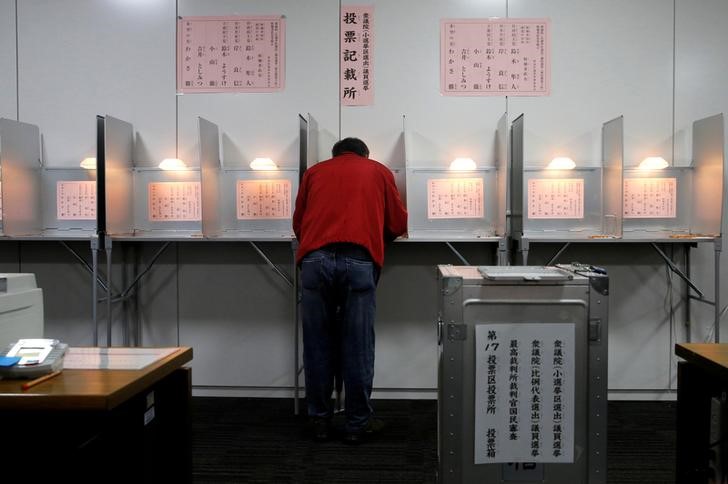 © Reuters. Man fills out his ballot for a national election at a polling station in Tokyo