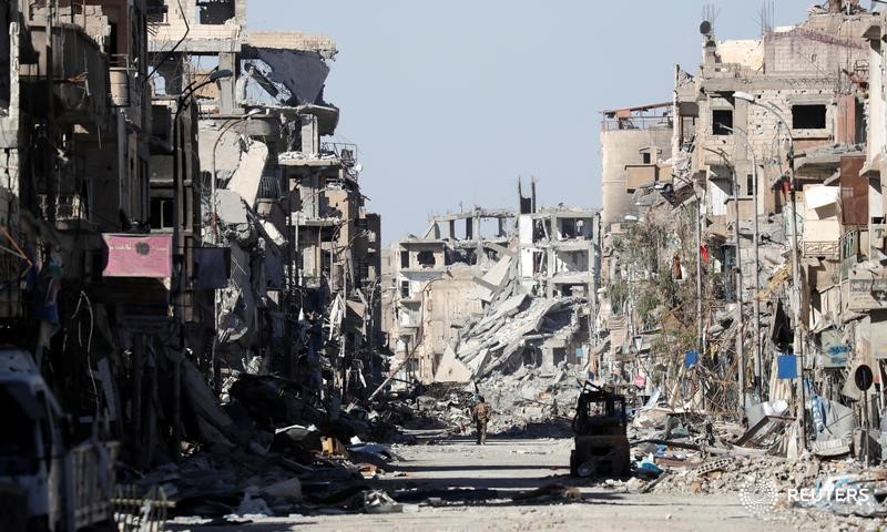 © Reuters. A fighter of Syrian Democratic Forces stands amidst the ruins of buildings near the Clock Square in Raqqa