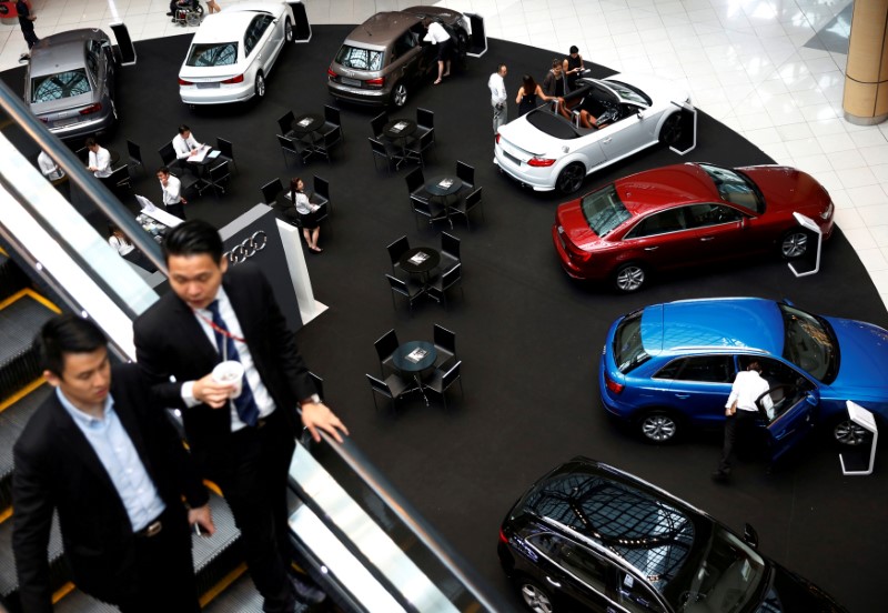 © Reuters. FILE PHOTO - People look at cars on display at a mall in Singapore