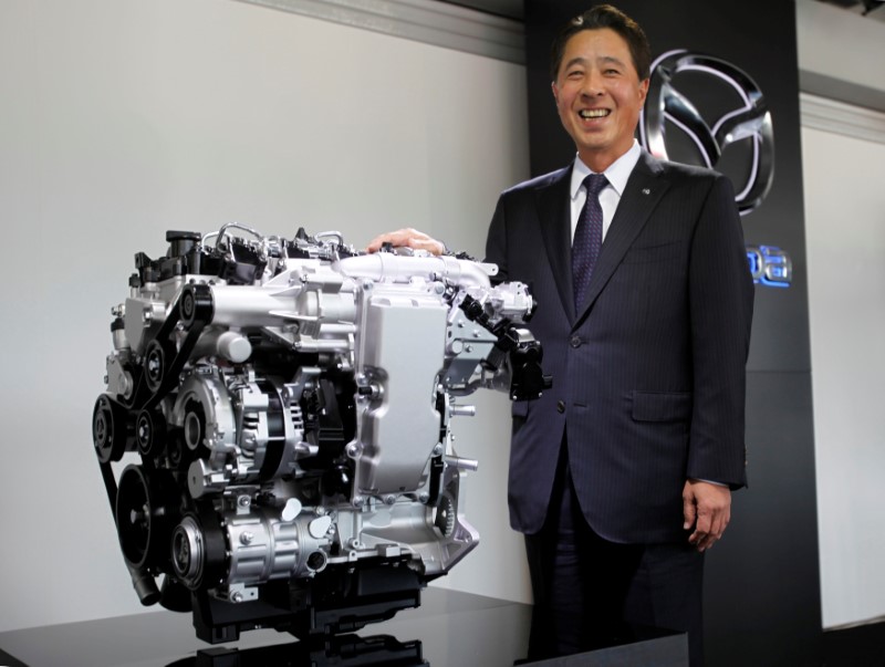 © Reuters. Mazda Motor President Masamichi Kogai poses with a model of its newly developed SKYACTIV-X engine at the company's proving ground in Mine,