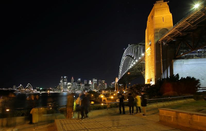 © Reuters. Sydney's central business district lights up on the opposite side of the Sydney Harbour Bridge as groups of tourists take photos from Milsons Point in central Sydney