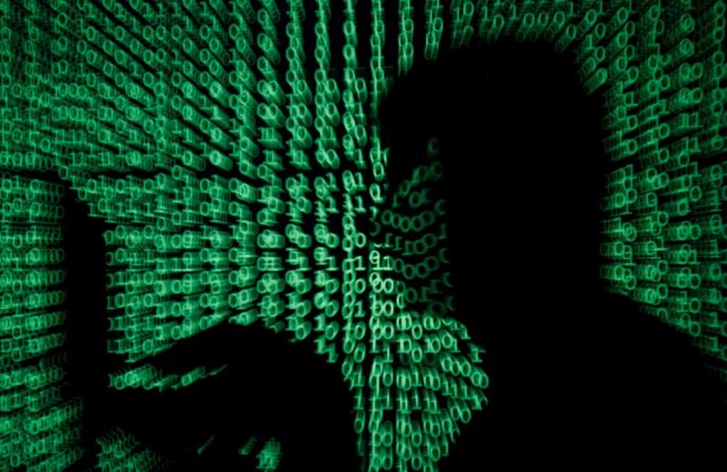 © Reuters. FILE PHOTO: Man holds laptop computer as cyber code is projected on him in this illustration picture