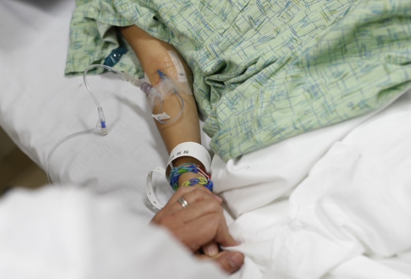 © Reuters. Doctor holds the hand of patient in the Emergency Room at OSF Saint Francis Medical Center in Peoria