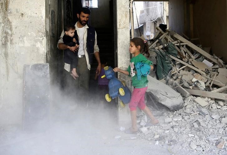 © Reuters. Menina segura brinquedo em local destruído por ataque aéreo em Ghouta