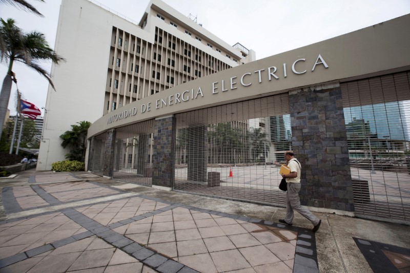 © Reuters. FILE PHOTO: A man walks past the headquarters of Puerto Rican power utility PREPA (also known as AEE) in San Juan