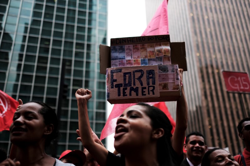 © Reuters. Members of Brazil's Homeless Workers' Movement (MTST) shout slogans holding a placard reading "Out Temer" during a vote on whether the Congress allows charges against President Michel Temer to be sent to the Supreme Court for trial, in Sao Paulo