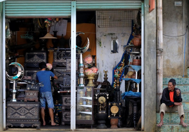 © Reuters. A worker cleans-up displayed antiques for sale inside a store in Marawi city