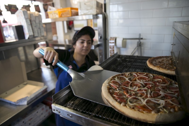 © Reuters. A worker takes a vegan pizza out of the oven at a Domino's Pizza restaurant in Tel Aviv