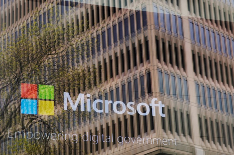 © Reuters. FILE PHOTO: An promotional video plays behind a window reflecting a nearby building at the Microsoft office in Cambridge