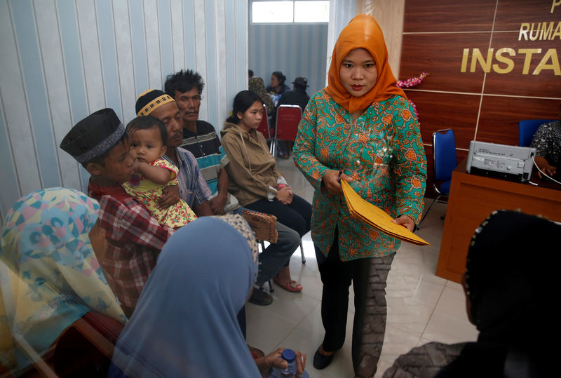 © Reuters. A hospital official talks to families looking for the bodies of their family members at a police hospital in Jakarta