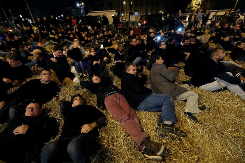 © Reuters. FILE PHOTO: French farmers sit on hay as they stage a demonstration on the Champs-Elysees avenue in Paris