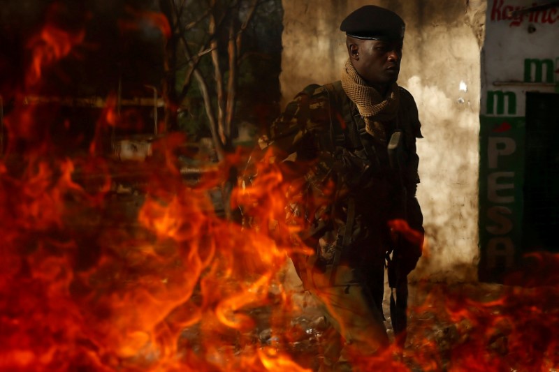 © Reuters. A police officer walks by a burning barricade during an opposition protest in the slum area of Mathare in the capital Nairobi