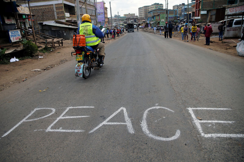 © Reuters. A man rides a motorbike past the word "Peace" in Kawangware slums in Nairobi