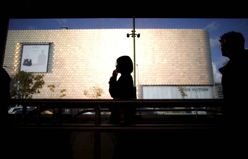 © Reuters. A woman is silhouetted against a department store at Apgujeong luxury shopping district in Seoul