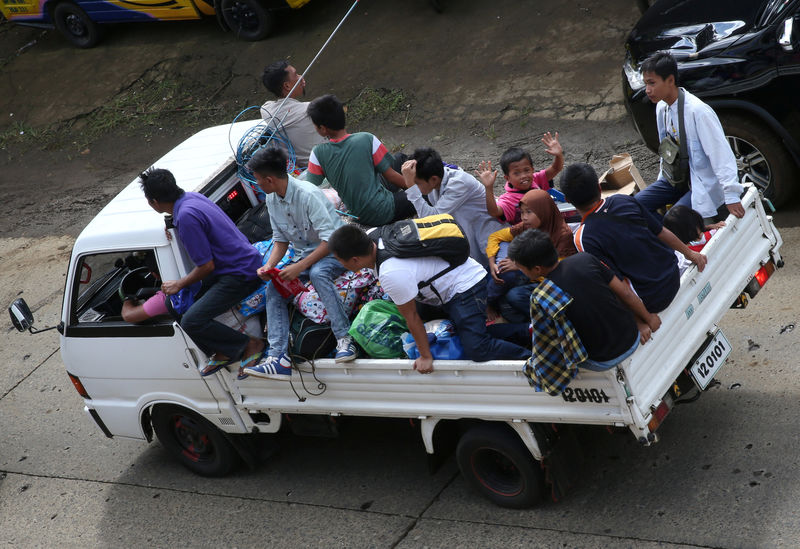 © Reuters. Residents who stayed at evacuation centers, due to the assault of government troops against pro-Islamic State militant groups, ride in a van with their belongings after they were allowed to return to their homes at Basak