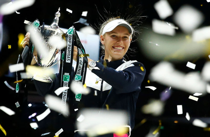 © Reuters. La tenista danesa Caroline Wozniacki celebra con el trofeo después de ganar el WTA Finals en el partido definitorio a la estadounidense Venus Williams