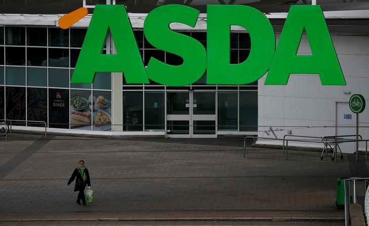 © Reuters. FILE PHOTO: An ASDA employee walks beneath a company logo outside a store in Manchester, northern England.