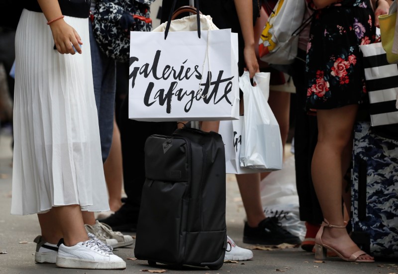 © Reuters. A Galeries Lafayette shopping bag is seen hanging on a tourist's travel bag in front of their their store in Paris