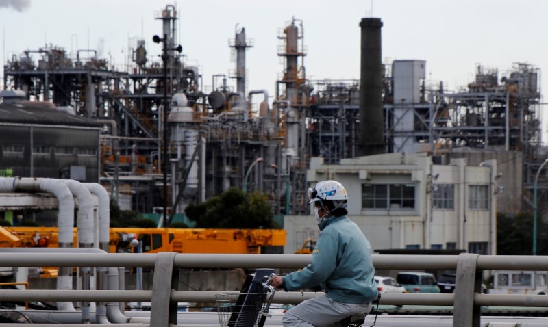 © Reuters. FILE PHOTO: Worker cycles near a factory at the Keihin industrial zone in Kawasaki,