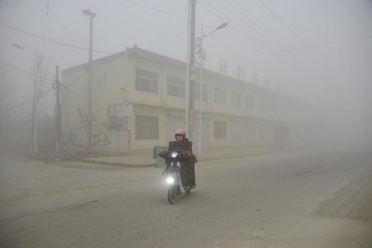 © Reuters. FILE PHOTO: A cyclist rides along a street in heavy smog during a polluted day in Liaocheng