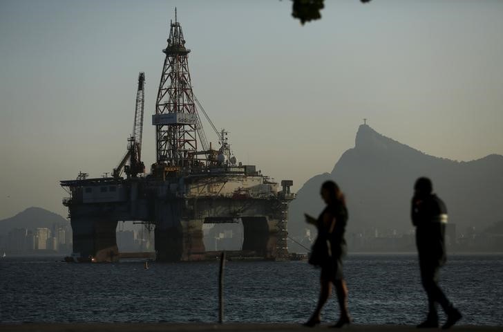 © Reuters. Pessoas passam por plataforma de petróleo em Niterói, no Rio de Janeiro