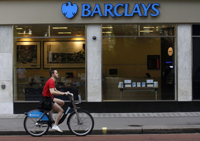 © Reuters. A man rides a bicycle past a Barclays bank in London
